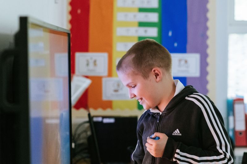 Boy interacting with a screen with a rainbow background